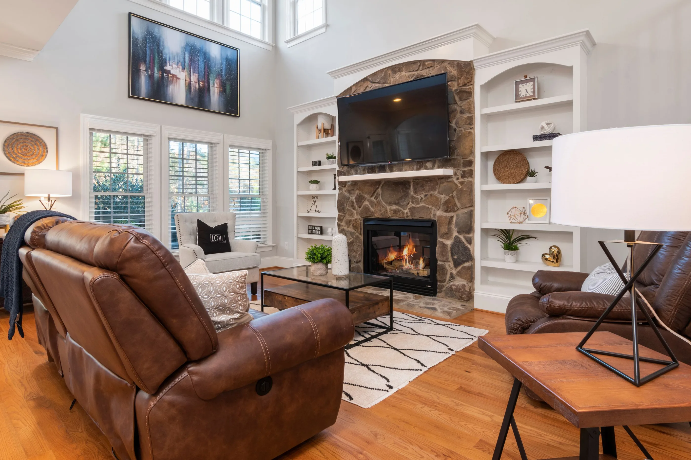 Family room with a stone fireplace and painted white built-ins