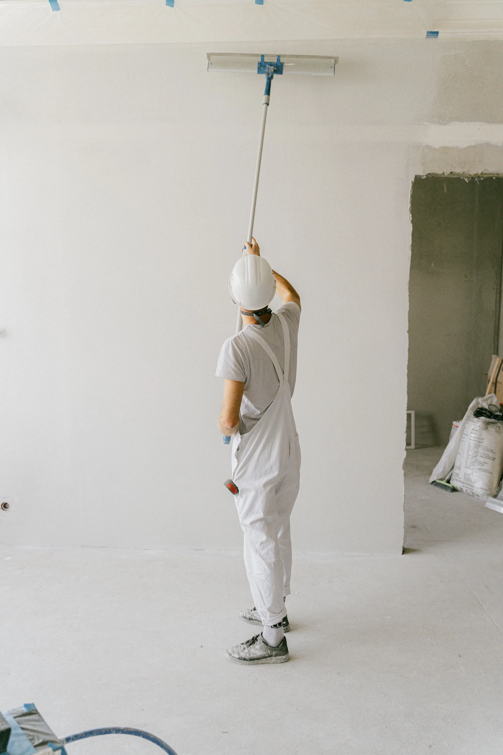 Professional painter rolling a ceiling in a fully prepared room